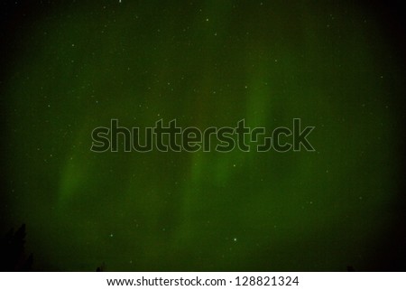 Green northern lights over the interior of Alaska during winter with stars in the background.