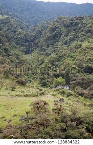 Mountainside in the Amazonian foothills of the Andes in Ecuador deforested for cattle pasture, with forested ravine and waterfall