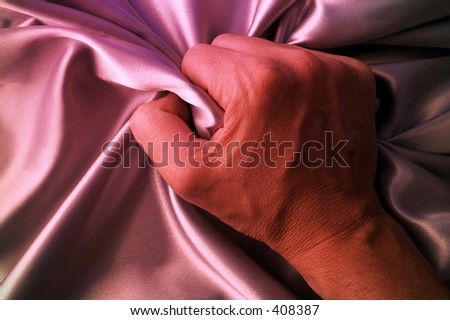 Man grabing satin sheet on the bed.