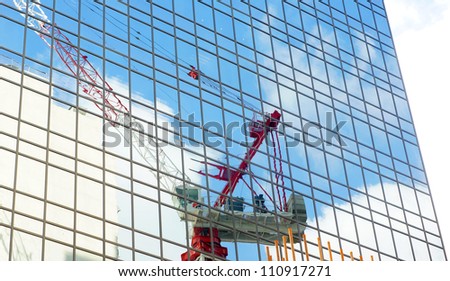 Urban development: hong kong tower Crane and clouds in the construction site with the reflection in mirror of nearby glass building