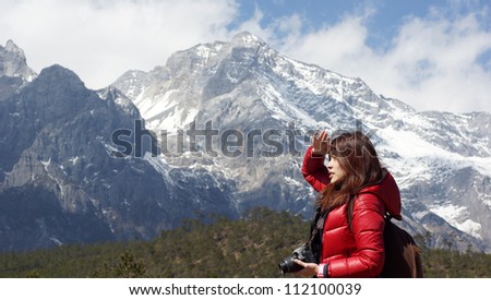 Chinese asian girl model under the snow mountain ridge background, fall into a trance, taking picture, taking photo in Lijiang, Yunnan province