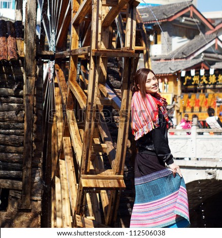 chinese girl model at Lijiang dancing in front of big waterwheel woman in  lijiang old town, the world heritage site of UNESCO