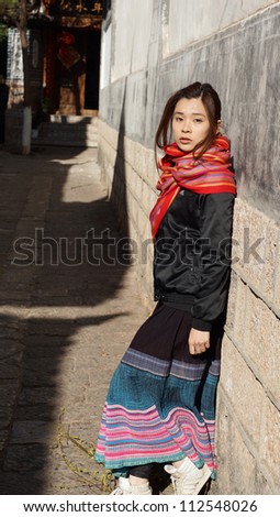 asian model with different pose with innocent face lying on the wall of old town, traditional dressing