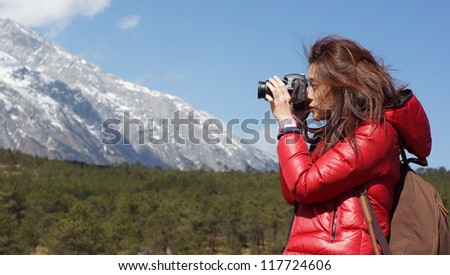 girl photographer take picture and focus on the beautiful snow mountain landscapes in China Yunnan province