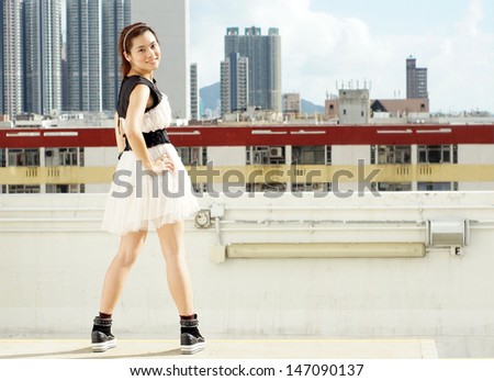 Happy pretty young city girl stand akimbo on the building roof,  stand up in the city life, face the difficult in hong kong china view