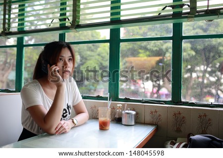 Young girl call many time, waiting someone who late and find him in old fashion chinese restaurant in hong kong