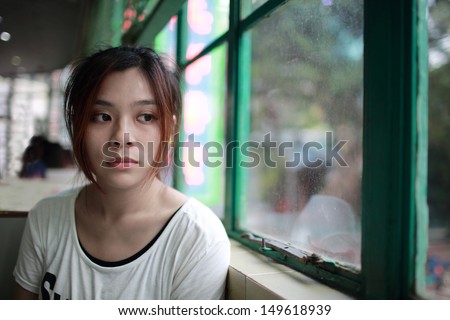 Sad woman waiting someone who is late, after cry,she look outside nearby window,  reflection on glasses in restaurant of Hong Kong