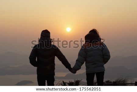 sweet couple found each other , special scenes, hand in hand under the first day sunrise a new year honeymoon , hiking on the peak, seaview landscape with beautiful skyline in good morning background