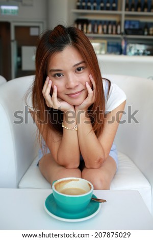 Beautiful Girl sit in cafe, cup of hot coffee is still not drunk, head in hands and watch in hong kong
