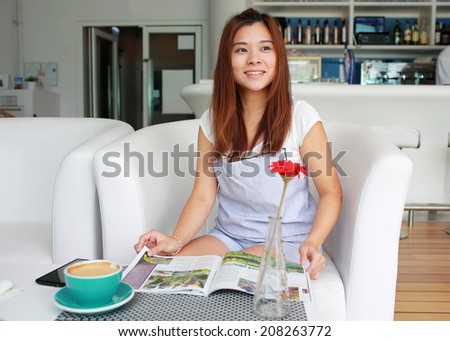 Beautiful girl reading magazine in tea time ,smile in cafe someone call her, hear good news and expect something