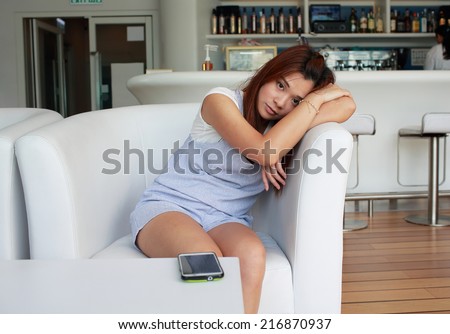 Girl feel unwell on sofa, feeling bad , do not want to pick up the phone call in restaurant / bar