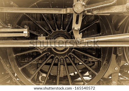 Steam train wheel assembly detail showing connecting rods and piston rods. Vintage sepia effect. Horizontal format.