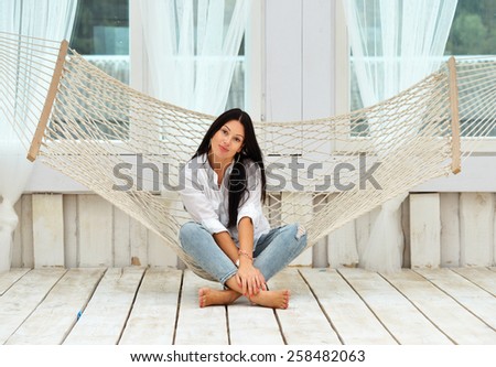 Beautiful young woman relaxing in hammock at home