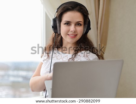 A girl with the head-phones working in a laptop.