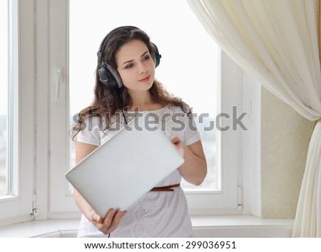 A girl with the head-phones working in a laptop.