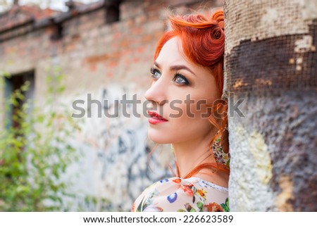 Red-head young woman near brick wall