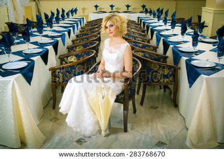 Beautiful blond bride in white dress near wedding table