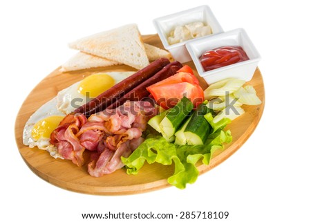 Tasty breakfast - toasts, fried egg, sausages, meat and vegetables on wooden board