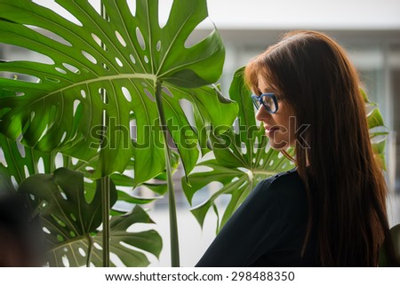 Young beautiful brunette woman on stairs over green leaves