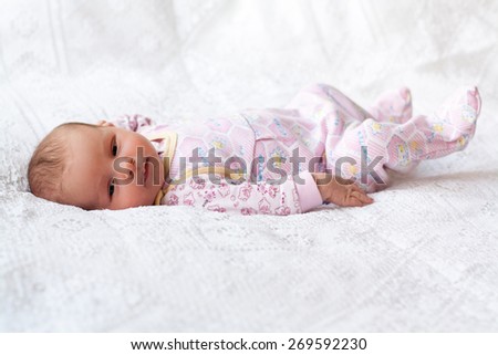 new born baby lying on texture blanket, light pink colors, looking at camera
