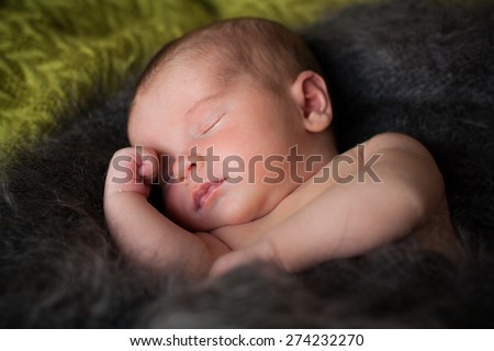 new born baby is sleeping in downy shawl, lying baby, eyes are closed, put out tongue