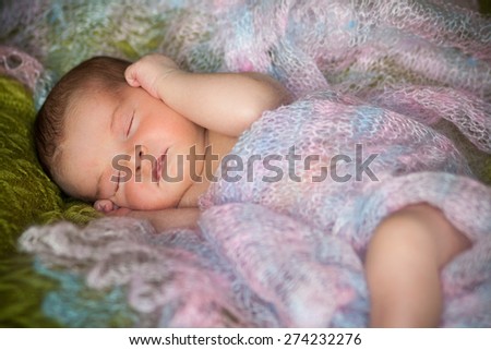 new born baby is lying in shawl, sleeping baby, eyes are closed, on blanket