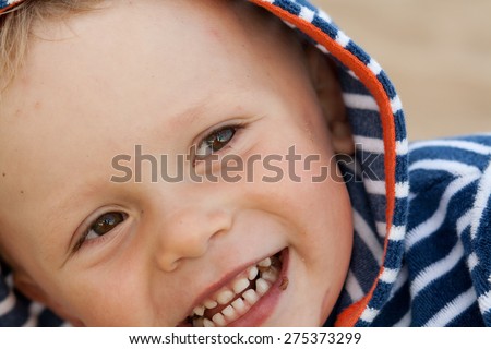 baby after chocolate eaten, messy around mouth after eating chocolate. Marine dress.Portrait at beach