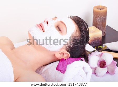 Young beautiful girl receiving pink facial mask