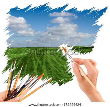 hand with paint brush painting a beautiful summer landscape with blue sky and clouds