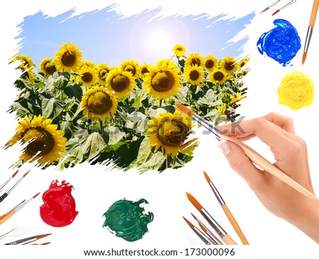 Hand with a brush painting summer landscape with sunflowers
