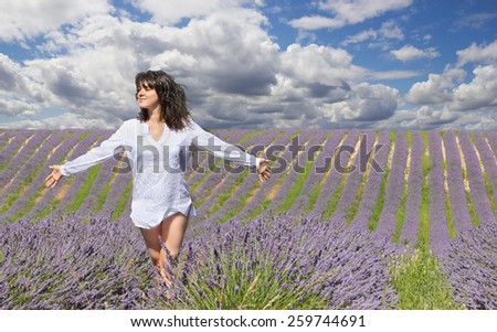 Beautiful young woman in summer day in lavender field with cloudy sky