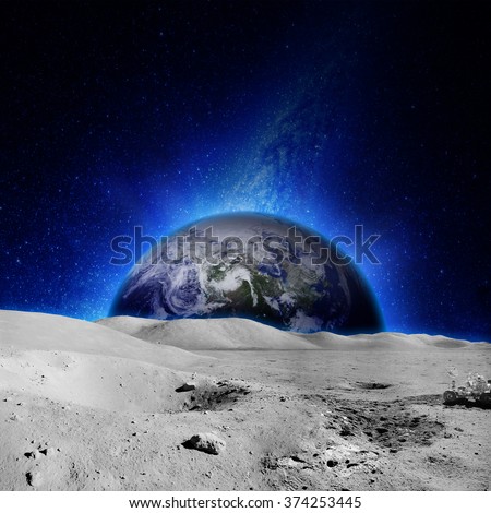 The moon\'s surface with glowing earth on the background. Elements of this image furnished by NASA.