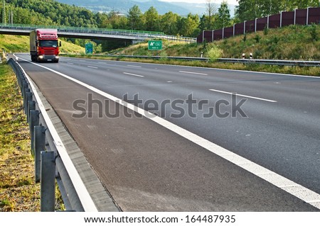Highway in landscape red truck arrives on the highway in the background the bridge and forest on the slope of the against the sound barrier Highway in landscape red truck arrives on the highway in the background the bridge and forest on the slope of the against the sound barrier