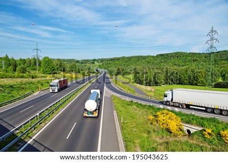 A country landscape with a highway, the highway goes truck and a tank truck, from the entrance to the highway coming white truck, in the distance electronic toll gate,  top view