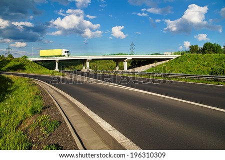 Bridge over an empty highway in the countryside, going over the bridge truck, blue sky with white clouds