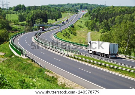 The highway between woods, in the middle of the highway electronic toll gates, moving trucks, in the distance Bridges