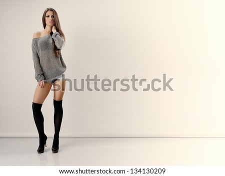 Young beautiful girl with very long dark hair/ Girl with long bare legs in a sensual pose on a light background