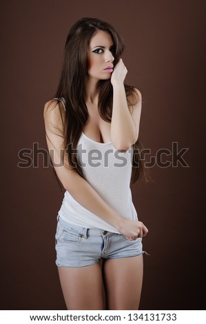 Woman leaning against brown background with hand in hair