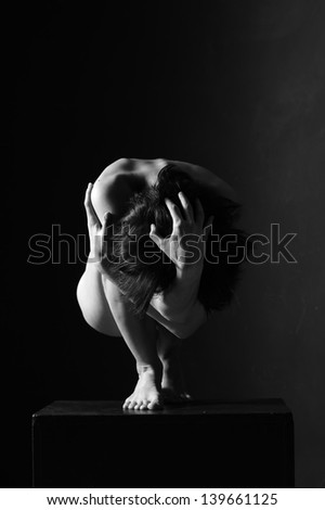 Naked beautiful woman relating to the white and the black background in the gymnastic figure