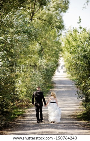 Married couple walking down a country road among trees