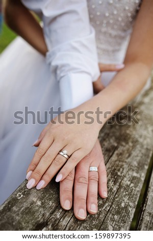 Wreathed hands of lovers. Hands of spouses being in the amorous touch on the wooden railing of stairs