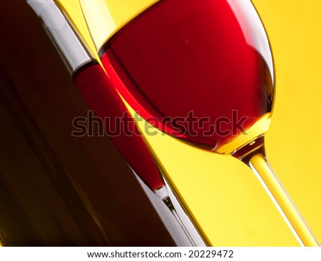 Glass and bottle of red wine on yellow background