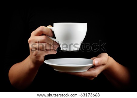 Cup of coffee in the women\'s hand on black background