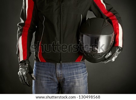 Biker with helmet in his hands. Dark background