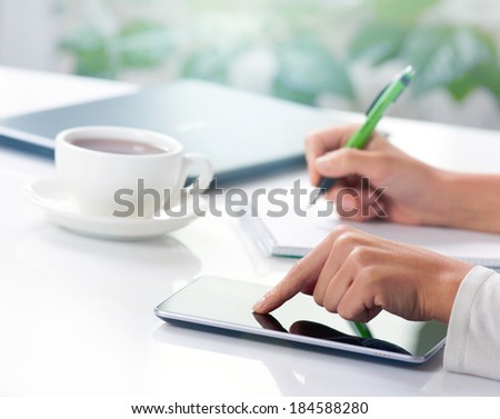 Woman hands with tablet PC and notepad at office