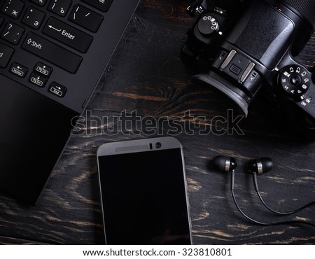 Laptop, smart phone, photo camera and headset on wooden background
