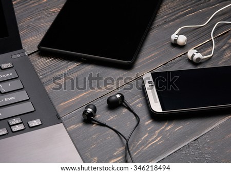 Laptop, smart phone, tablet pc and headset on wooden background