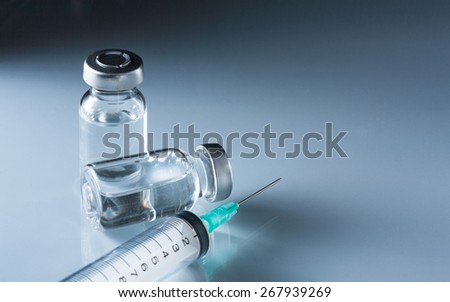 medical ampules and syringe on blue background