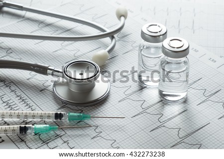 Stethoscope medical ampules and syringe on EKG graph background
