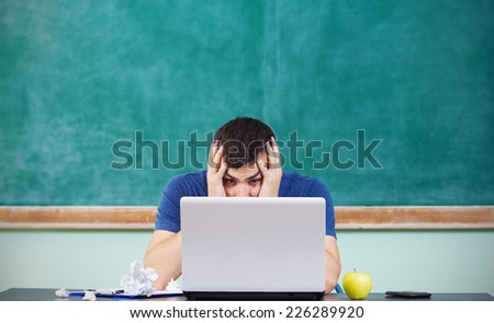 Stressed overworked man studying in front of notebook.